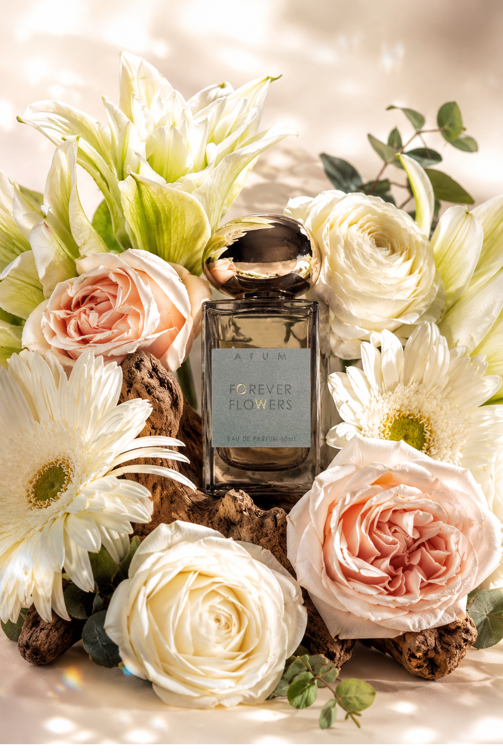 A rectangular glass perfume bottle labeled 'ETUM FOREVER FLOWERS' sits centered among white and blush roses, daisies, and green leaves on a softly lit beige background.