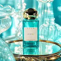 A bottle of ATUM JEWEL Eau de Parfum with a square turquoise glass body, a white label, and a reflective gold cap, displayed on a gold tray with a turquoise background of glass decanters.