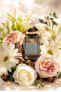 A rectangular glass perfume bottle labeled 'ETUM FOREVER FLOWERS' sits centered among white and blush roses, daisies, and green leaves on a softly lit beige background.